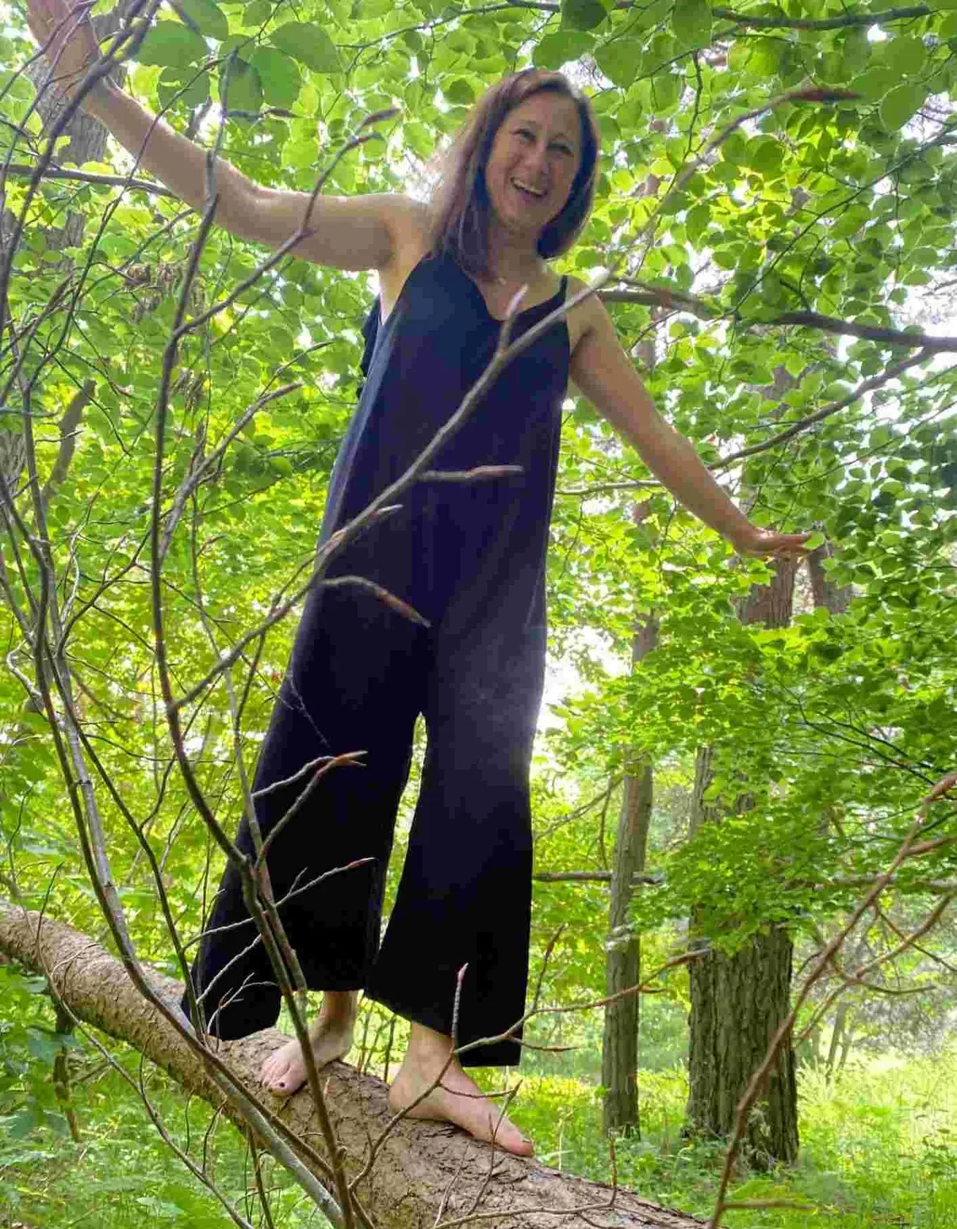 femme qui rie et marche sur un tronc